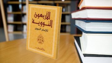كتاب الإرشاد النوي للإمام النووي، يظهر على طاولة خشبية بجانب مجموعة من الكتب الأخرى، مع خلفية مكتبة blurred.