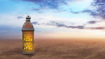 فانوس مزخرف مضاء في مشهد صحراوي تحت سماء مع سحب، يرمز إلى الأجواء الرمضانية والتقاليد الثقافية.