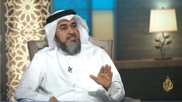 رجل يرتدي الثوب والشماغ، يجلس في استوديو تلفزيوني، يتحدث أثناء المقابلة. خلفية الاستوديو تتضمن إضاءة ناعمة وزخارف تقليدية.