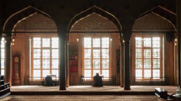 مشهد داخلي لمكتبة تقليدية، يظهر شخصان يجلسان على الأرض أمام نوافذ كبيرة، مع تصميم معماري مميز وقباب. الأرفف مليئة بالكتب، والإضاءة الطبيعية تخلق جواً هادئاً وملهمًا.