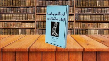 كتاب بعنوان "الرد على من قال ببدعة المولد" يظهر في مكتبة تحتوي على رفوف من الكتب القديمة. الغلاف الأزرق يضم رسماً لشخصية تاريخية مع نص عربي. تعكس الصورة التراث الثقافي والكتب الإسلامية.