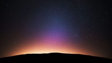 سماء مرصعة بالنجوم فوق أفق مظلم، مع تدرجات لونية زرقاء وبنفسجية تتداخل في الأفق.