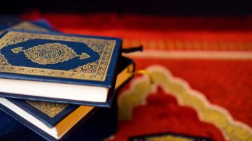 كتب القرآن الكريم موضوعة على سجادة حمراء مزخرفة، مع تفاصيل ذهبية على الأغلفة.