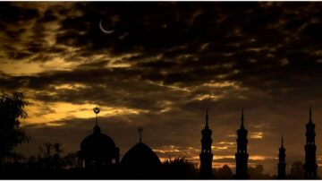 غروب الشمس مع هلال في السماء، يبرز صومعة مساجد وأبنية ذات قباب في ظل غامق، ما يخلق مشهداً روحياً وجميلاً يعكس جمال العمارة الإسلامية.