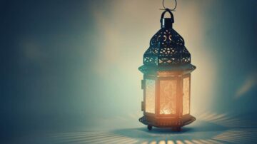 فانوس مزخرف بإضاءة دافئة، يضيء بتصميمه الفريد، مع ظلال تبرز جماله في الخلفية الناعمة.