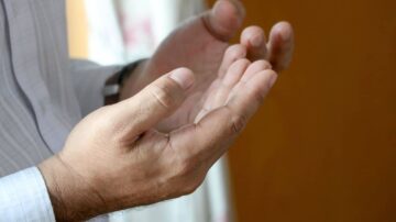 يدين مفتوحتين في وضع الدعاء أو النداء، تعكسان الاستعداد للتواصل الروحي أو التعبير عن الأمل.