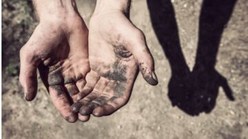 يدان مكشوفتان مع آثار الأوساخ، تظهران في ضوء النهار، بينما تلقي الظلال شكلًا مميزًا على الأرض. تعكس الصورة العمل الشاق والاتصال بالطبيعة.