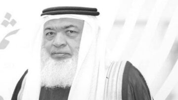 صورة لرجل يرتدي الزي التقليدي العربي مع عقال وعباءة، يظهر في خلفية بسيطة. تعكس الصورة هيبة وثقافة المنطقة.