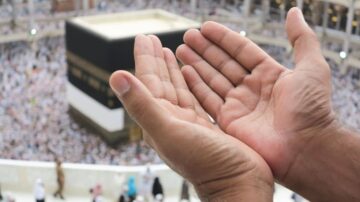 أيدٍ مرفوعة للدعاء أمام الكعبة المشرفة في مكة المكرمة، مع حشود من الحجاج في الخلفية، تعكس روح العبادة والت devotion.