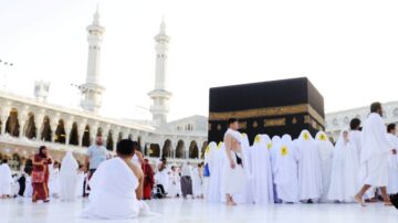 مشهد للحجاج أثناء أداء مناسك العمرة حول الكعبة في المسجد الحرام بمكة، مع وجود معالم إسلامية واضحة وأشخاص يرتدون الإحرام.