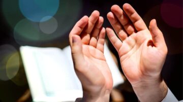 أيدٍ مرفوعة في الدعاء مع كتاب مفتوح في الخلفية، تعبير عن الإيمان والتأمل الروحي.