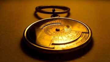 بوصلة معدنية قديمة بتصميم دائري، تتألق بلون ذهبي تحت ضوء خافت، تعرض قياسات مختلفة على سطحها.