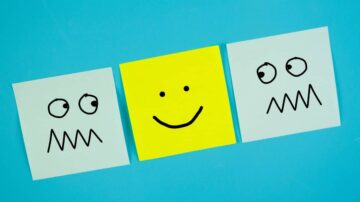 ملاحظات ملونة على خلفية زرقاء، تحتوي على رموز تعبيرية؛ ورقة صفراء في المنتصف تحمل وجه مبتسم، وورقتان زرقاوتان على الجانبين تحملان وجوهًا مع تعبيرات مضحكة.