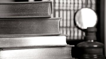 كتب قديمة مكدسة في المقدمة مع عدسة مكبرة وزجاجة في الخلفية، تعكس أجواء القراءة والمكتبات.