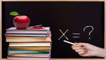 صورة تحتوي على كومة من الكتب الملونة بجانب تفاحة حمراء وأدوات مكتبية، مع يد تحمل طبشورة تشير إلى معادلة رياضية غير مكتملة مكتوبة على السبورة.