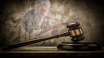 مطرقة قانونية موضوعة على طاولة، مع صورة خفية لرجل مسن يكتب على ورقة خلفها. تعبر الصورة عن العدالة والقانون.