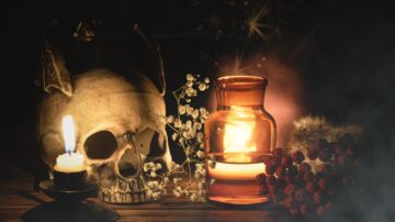 صورة لسكال وعاء زجاجي مضاء، محاط بشموع وزهور جافة، مع تأثيرات ضبابية وخلفية داكنة، تعكس أجواء غامضة وساحرة.