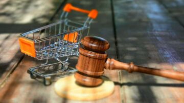 صورة تظهر مطرقة قاضي بجانب عربة تسوق صغيرة على سطح خشبي. تعكس الصورة تداخل عالم القضاء والتجارة، مما يرمز إلى القضايا القانونية المتعلقة بالتسوق والبيع.