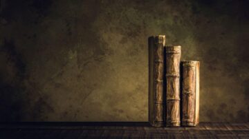 مجموعة من ثلاثة كتب قديمة ذات غلاف خشبي، موضوعة بشكل عمودي على سطح خشبي، مع خلفية داكنة ومجموعة من الألوان الترابية، تعكس أجواء تاريخية.