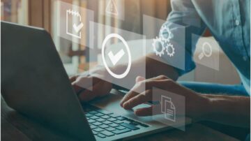 شخص يستخدم حاسوبًا محمولًا مع ظهور أيقونات تمثل التحقق والإعدادات والبحث، مما يدل على بيئة عمل رقمية منظمة وفعالة.