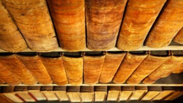 رفوف تحتوي على كتب قديمة ذات غلاف جلدي بني، تظهر من منظور سفلي. تعكس الكتب تاريخ المعرفة والثقافة.