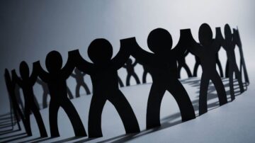 مجموعة من الأشخاص المصنوعين من الورق الأسود، متصلين بأيديهم لتشكيل دائرة. تعبر الصورة عن الوحدة والتعاون المجتمعي.