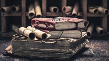 كتب قديمة مكدسة، مع دفاتر جلدية ولفائف ورقية، خلفية تحتوي على صناديق خشبية تحمل لفائف إضافية. الإضاءة الخافتة تضفي جواً تاريخياً.