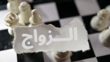 مجموعة من قطع الشطرنج البيضاء على رقعة الشطرنج، مع ورقة مكتوب عليها "الزواج" بشكل بارز في المقدمة.