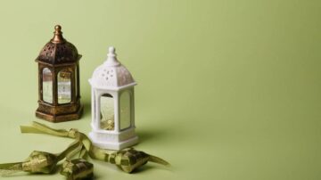 فوانيس مزخرفة بالألوان البرونزية والبيضاء على خلفية خضراء، مع شرائط زينة تتدلى بجانبها، تعكس أجواء الاحتفالات والمناسبات الخاصة.