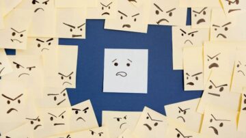 ورقة بيضاء في وسط مجموعة من أوراق ملاحظات صفراء تحمل وجوه تعبيرية غاضبة. تعبر الورقة البيضاء عن الحزن أو الاستياء وسط مشاعر الغضب المحيطة بها.