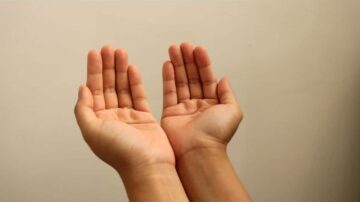 يدين مفتوحتين في وضعية الدعاء أو الاستقبال، مع خلفية بلون محايد.