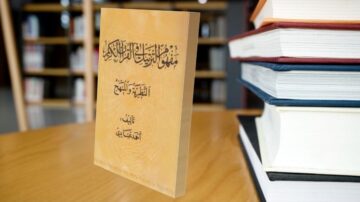 كتاب معنون "منهجية البحث العلمي" موضوع على طاولة بجانب مجموعة من الكتب المكدسة، يظهر تصميمه الخارجي باللون البيج مع نص عربي بارز، مما يعكس أهمية البحث العلمي في التعليم.
