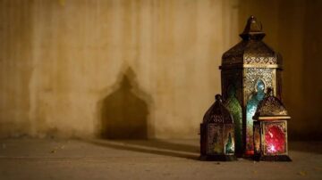 فوانيس ملونة بتصميمات معقدة، موضوعة على سطح خرساني، تلقي ظلالاً جميلة على الجدار الخلفي.