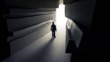 رجل يقف في ممر ضيق بين كومة من الكتب، مضاءً من الخلف، مما يخلق جوًا غامضًا يعكس البحث عن المعرفة والاكتشاف.