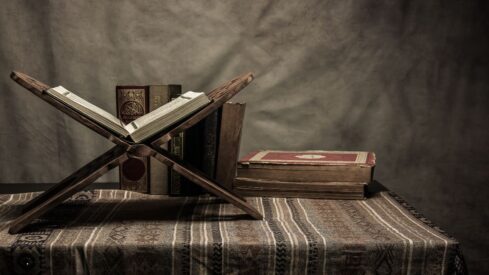 Wooden desk with office supplies, books, and writing tools on polished hardwood floor in still life composition