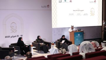 ندوة تتناول الثقافة العربية في مؤتمر يقام في 25-10 فبراير 2025. يظهر في الصورة متحدث يتحدث في الخلفية بينما تجلس ثلاث نساء في المقدمة، يرتدين ملابس تقليدية. الحضور يتابعون الجلسة بتركيز.