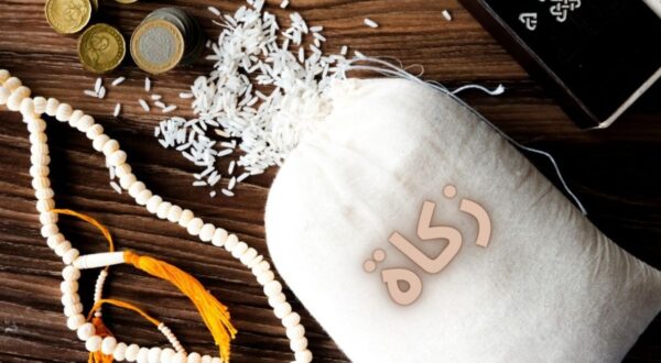 كيس من الأرز مملوء بالزكاة مع حبات من الأرز المتناثرة وحبات نقدية، بجانب مسبحة تقليدية.