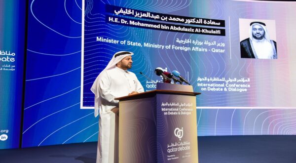 وزير الدولة، وزارة الخارجية، قطر، الدكتور محمد بن عبد العزيز الخليفي، يتحدث في مؤتمر دولي حول النقاش والحوار، مع خلفية تعرض معلومات المؤتمر والشعار.