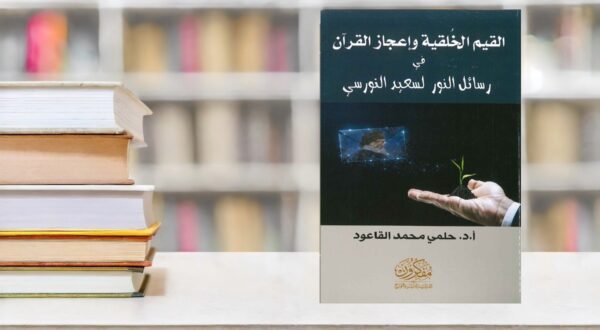 كتاب "القيم الخلقية وإعجاز القرآن في رسائل النور " للدكتور حلمي محمد القاعود، موضوعه يتناول القيم الأخلاقية وإعجاز القرآن، مع صورة تظهر يد تُشير إلى ورقة خضراء، محاطًا بمجموعة من الكتب على رف.