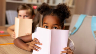 طفلتان تجلسان في فصل دراسي كلتاهما مهتمتين بالقراءة.