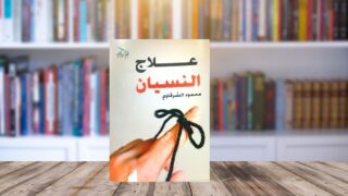 غلاف كتاب "علاج النسيان" لمحمود الشنّاوي، يظهر يد تمسك بخيط أسود، والخلفية تضم رفوف مكتبة مليئة بالكتب.