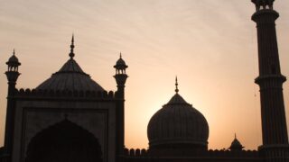 Silhouette of historic domes and minarets against a sunset sky, showcasing the architectural beauty of a mosque.