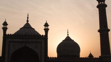 Silhouette of historic domes and minarets against a sunset sky, showcasing the architectural beauty of a mosque.