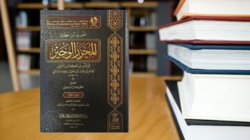 كتاب يتحدث عن تفسير القرآن الكريم، مع غلاف فخم باللون الأسود وعنوان بارز بالذهبي. يظهر الكتاب بجانب مجموعة من الكتب الأخرى على طاولة خشبية.
