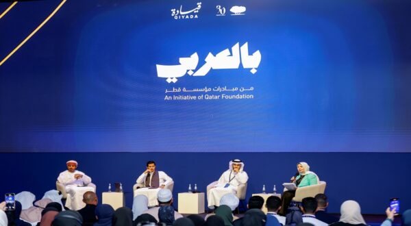 فعالية "بالعربي" من مؤسسة قطر، تتضمن مناقشة بين أربعة متحدثين على منصة، مع جمهور متنوع من الطلاب. يتواجد خلفهم شعار مؤسسة قطر.