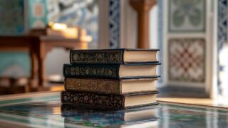كتابان ملونان بشكل جميل موضوعة فوق بعضها البعض، مع تفاصيل زخرفية واضحة، في بيئة تحتوي على زخارف معمارية تقليدية. الضوء الطبيعي يضيء المساحة، مما يبرز جمال الكتب والتفاصيل المحيطة بها.