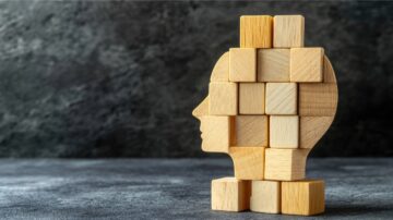 كتل خشبية مصممة على شكل رأس بشري، تشير إلى التفكير والإبداع، مع خلفية رمادية داكنة.