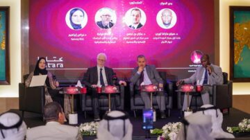 حدث ثقافي في الدوحة يضم أربعة متحدثين بارزين يتناولون مواضيع أدبية وثقافية. على اليسار، امرأة ترتدي الحجاب تحمل ملاحظات، بينما يجلس ثلاثة رجال على المنصة. يظهر في الخلفية شعار كتارا، مع تفاعل من الجمهور في المقاعد.