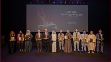 حفل تكريم الفائزين بجائزة كتارا للرواية العربية 2025، مع مجموعة من الفائزين يقفون على المسرح حاملين جوائزهم. خلفهم شاشة تعرض شعار الجائزة وتاريخ الدورة. تظهر الفائزة والمشاركون في أزياء تقليدية وحديثة، مع تعبيرات الفخر والاحتفال.