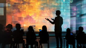 رجل يتحدث أمام شاشة عرض كبيرة تعرض رسومات بيانات ملونة، مع تواجد طلاب يجلسون في الصفوف الأمامية يحملون أجهزة لوحية. المشهد يبرز تفاعل التعليم التكنولوجي والابتكار في الفصول الدراسية.